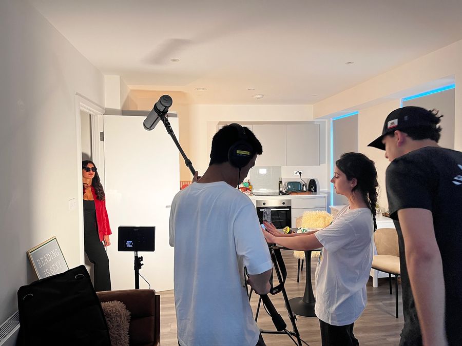 Behind the scenes on On Air: Asma directing a scene in a flat, with the boom operator and crew