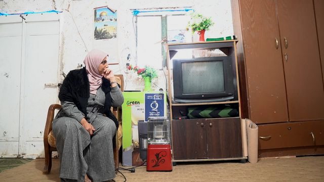 Women in Exile: a woman waiting beside an old television